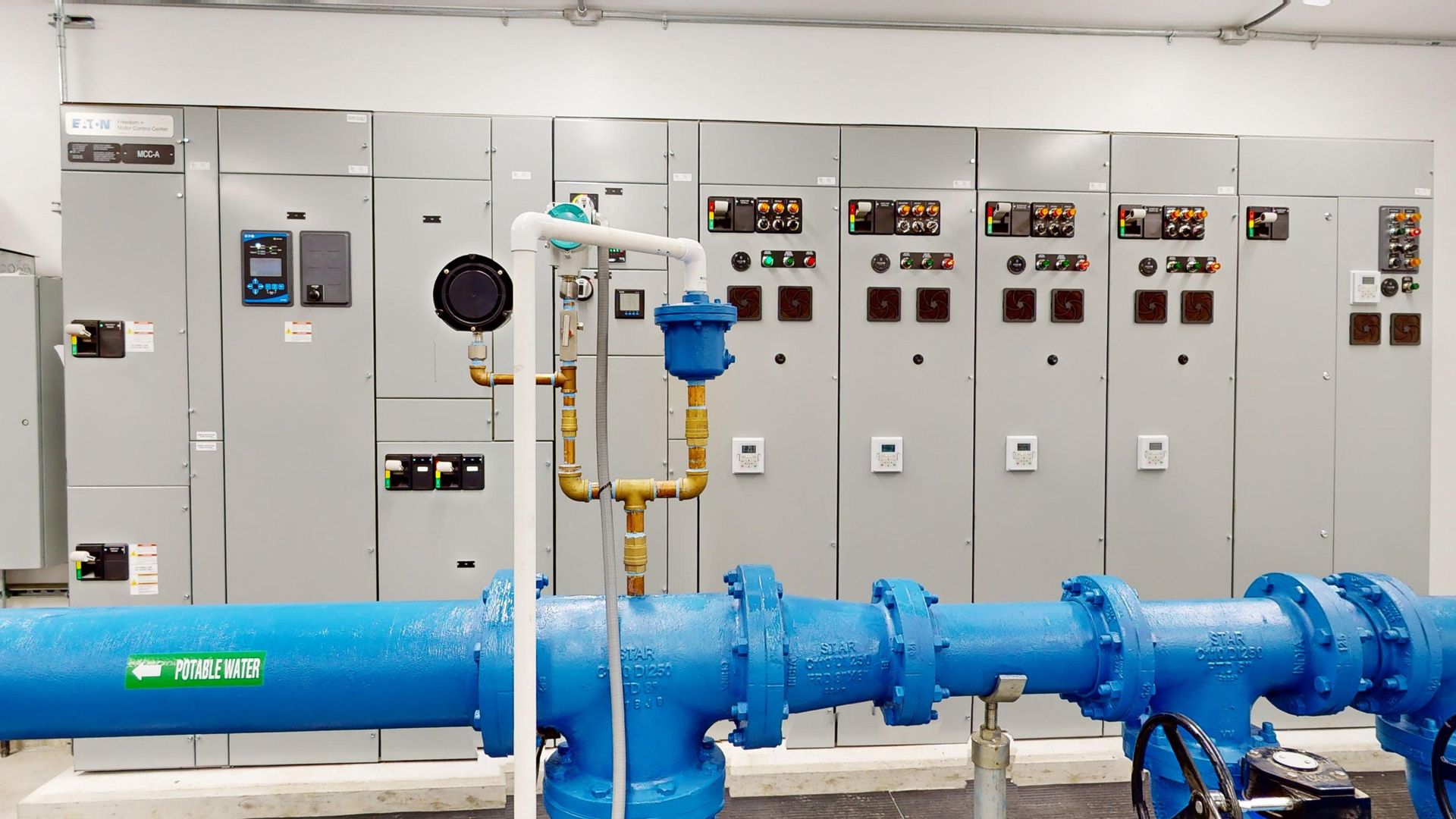 A room with a lot of blue pipes and electrical panels.