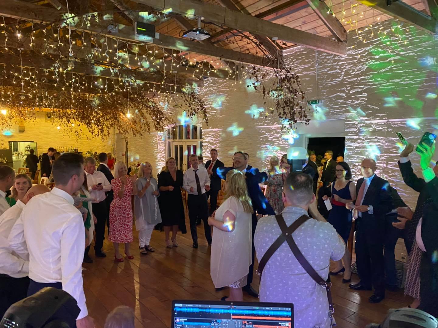 Party with people dancing in a venue with lights and a DJ setup.