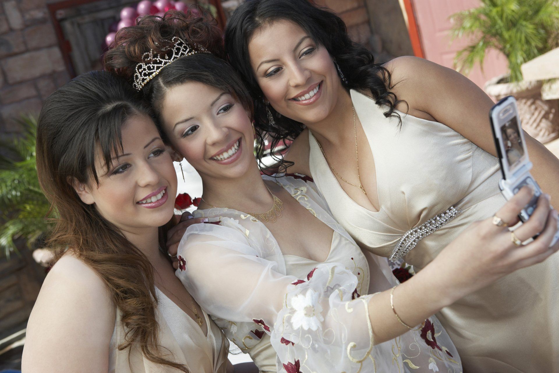 Girl (13-15) taking self-portrait with two friends using mobile phone at Quinceanera