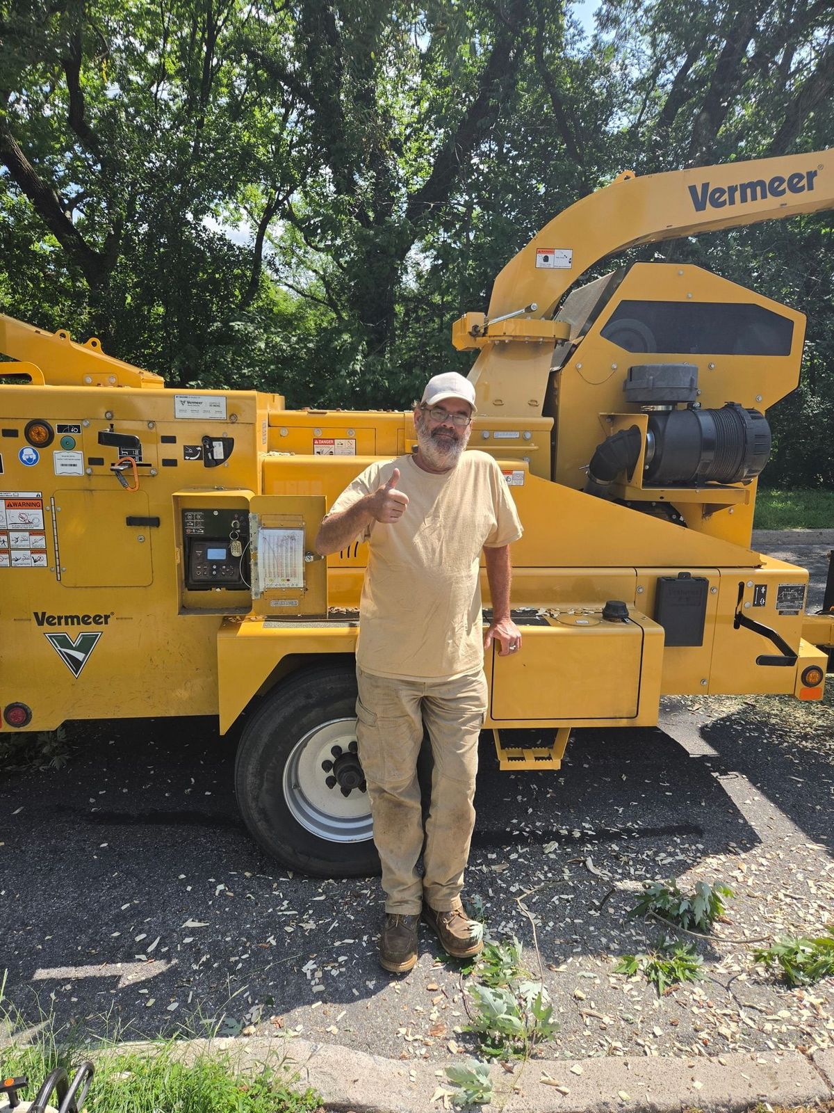 Eco Tree Service crew member standing beside the Vermeer wood chipper on a job site