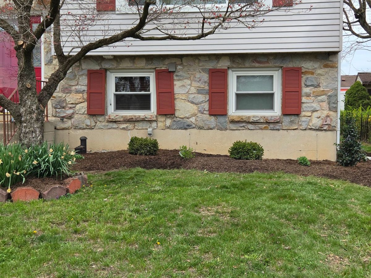 Finished mulch beds with fresh dark mulch and newly planted shrubs along a stone home in Bethlehem, PA