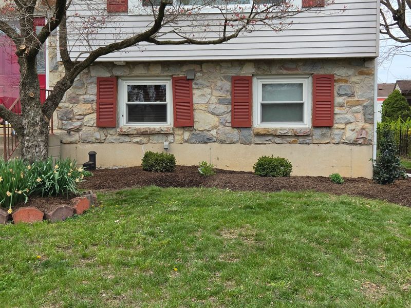 Finished mulch beds with fresh dark mulch and newly planted shrubs along a stone home in Bethlehem, PA