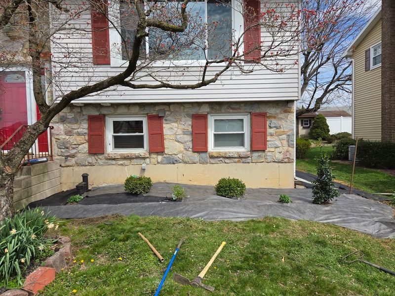 New landscape fabric and young shrubs laid out along the front of a stone home in Bethlehem, PA