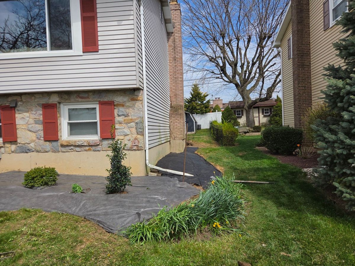 Side yard bed prepared with landscape fabric and a new shrub at a stone home in Bethlehem, PA