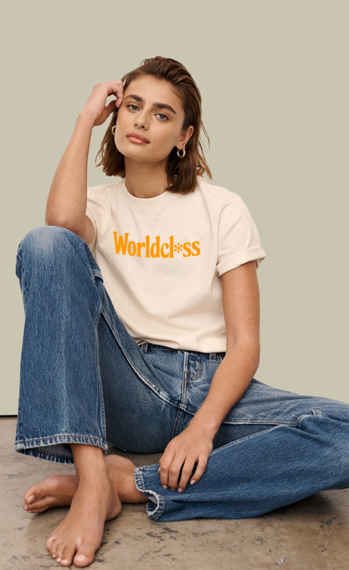 a woman is sitting on the floor wearing a t-shirt and jeans .