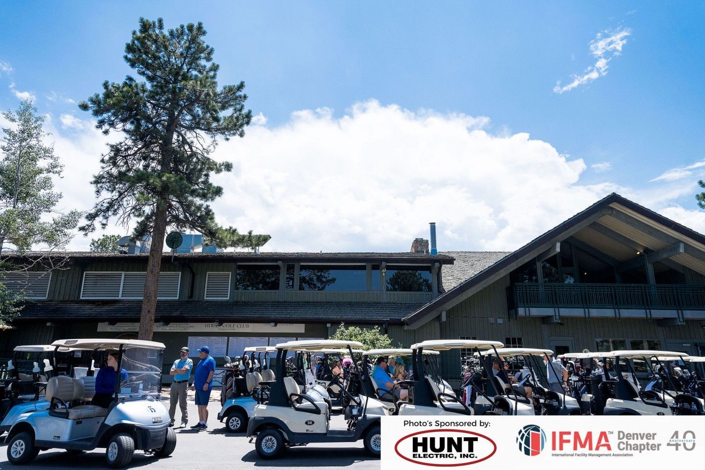 Golf carts parked in front of a building with people nearby. Sky is blue with puffy clouds.