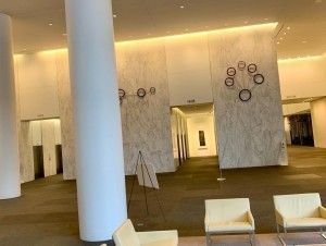 Modern lobby with marble walls, white columns, and cream-colored seating.