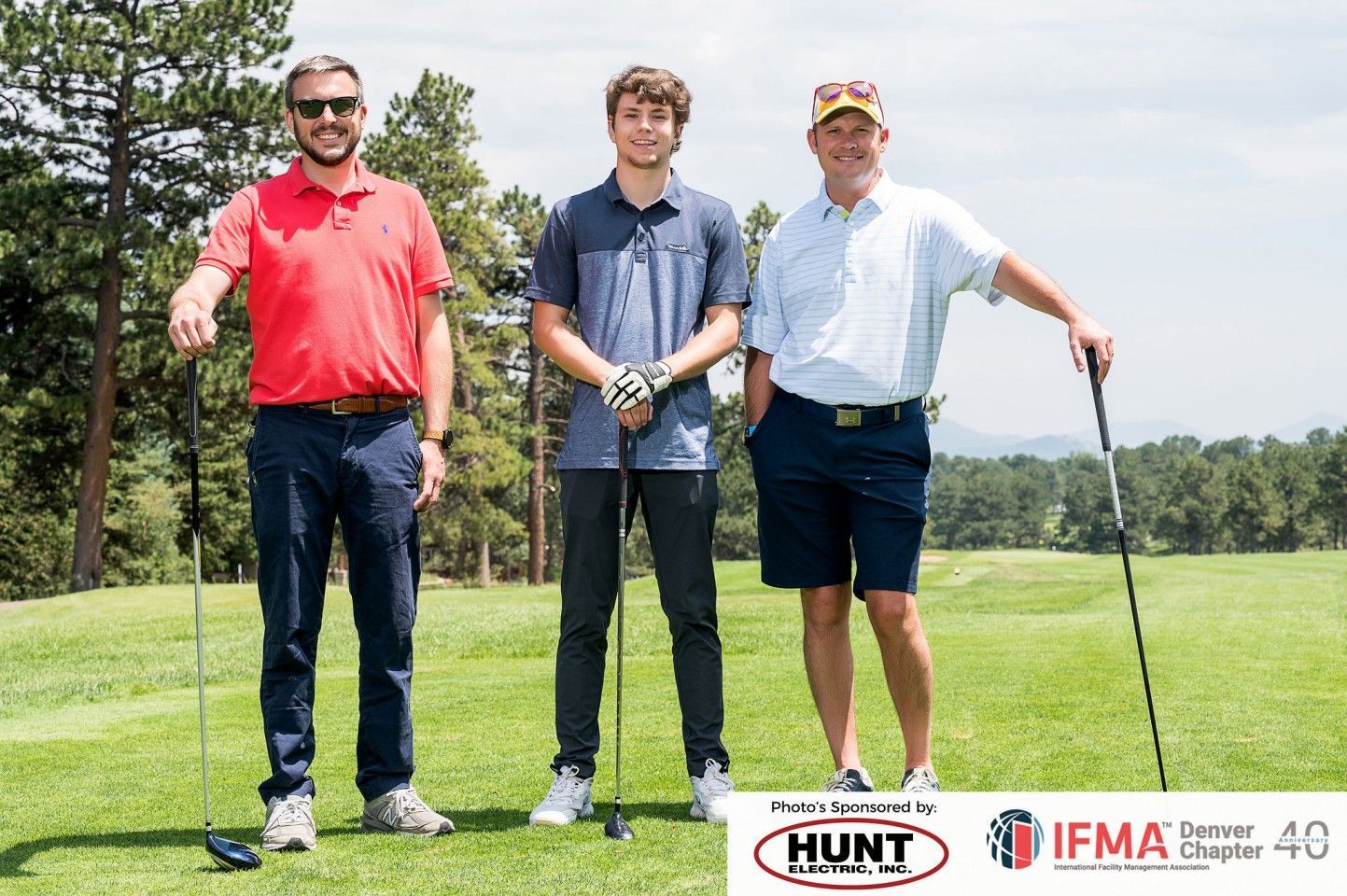 Three men standing on a golf course holding clubs.