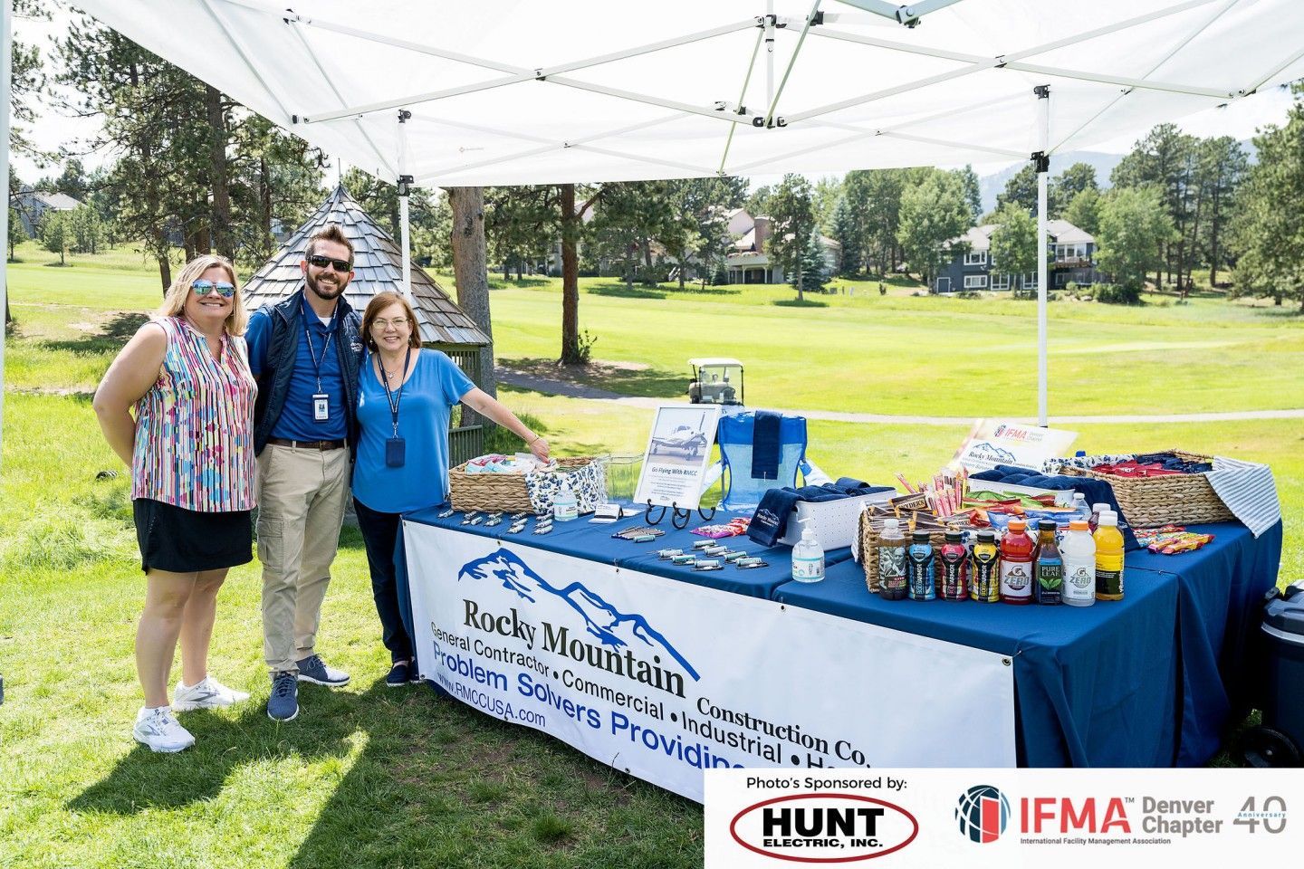Three people stand at a booth with a banner 