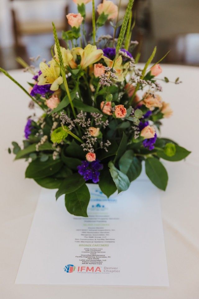 Floral centerpiece atop a menu on a white tablecloth, likely at an event.