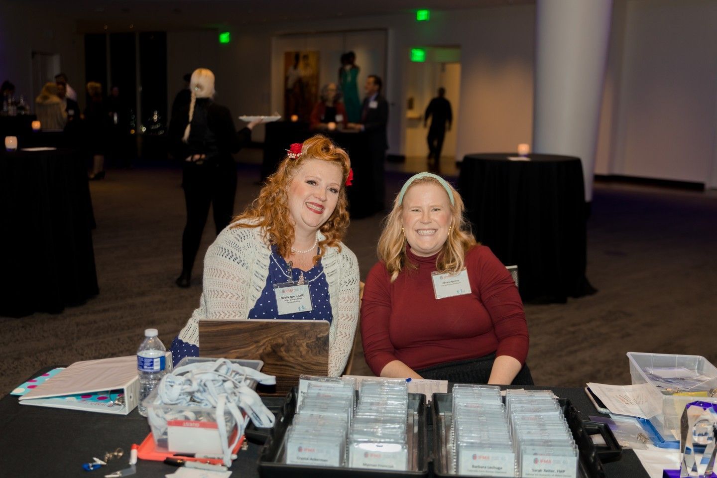 Two women smiling at a registration table at an event.
