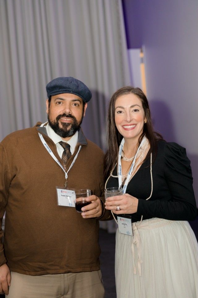 Man in cap and woman with drinks at event.