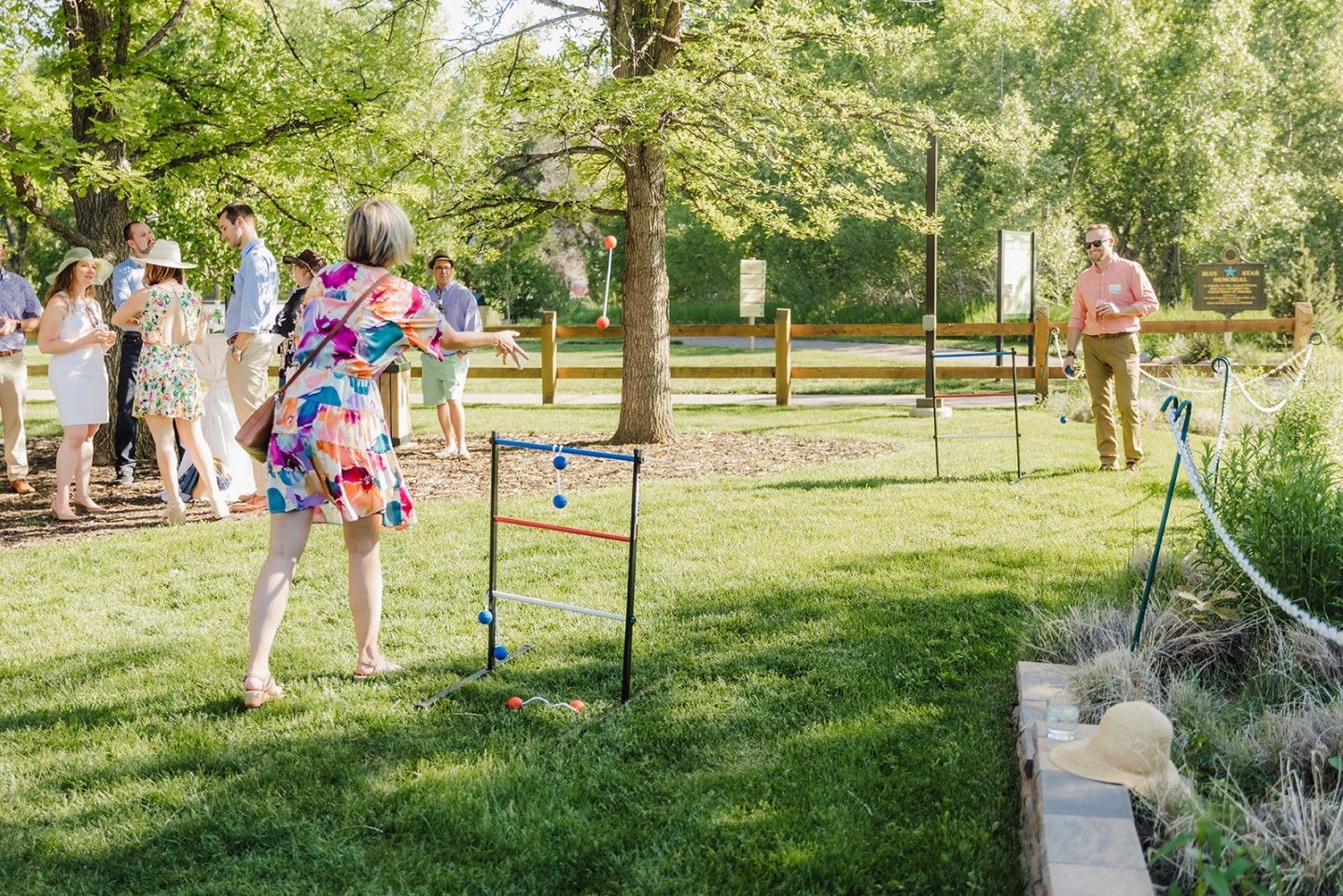 People playing a ladder toss game outdoors on a sunny day.