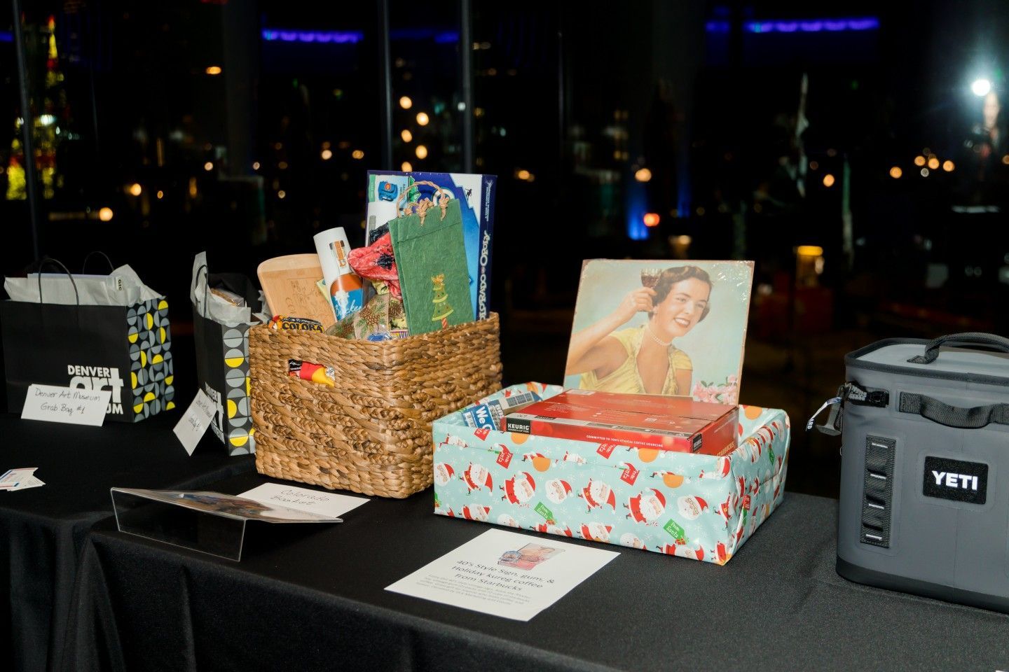 A table with gift baskets and a cooler, possibly for an auction. Evening setting.