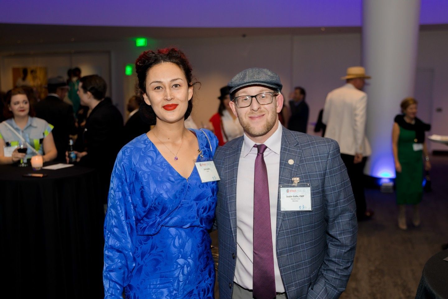 Woman in blue dress and man in tweed jacket pose together at an event.