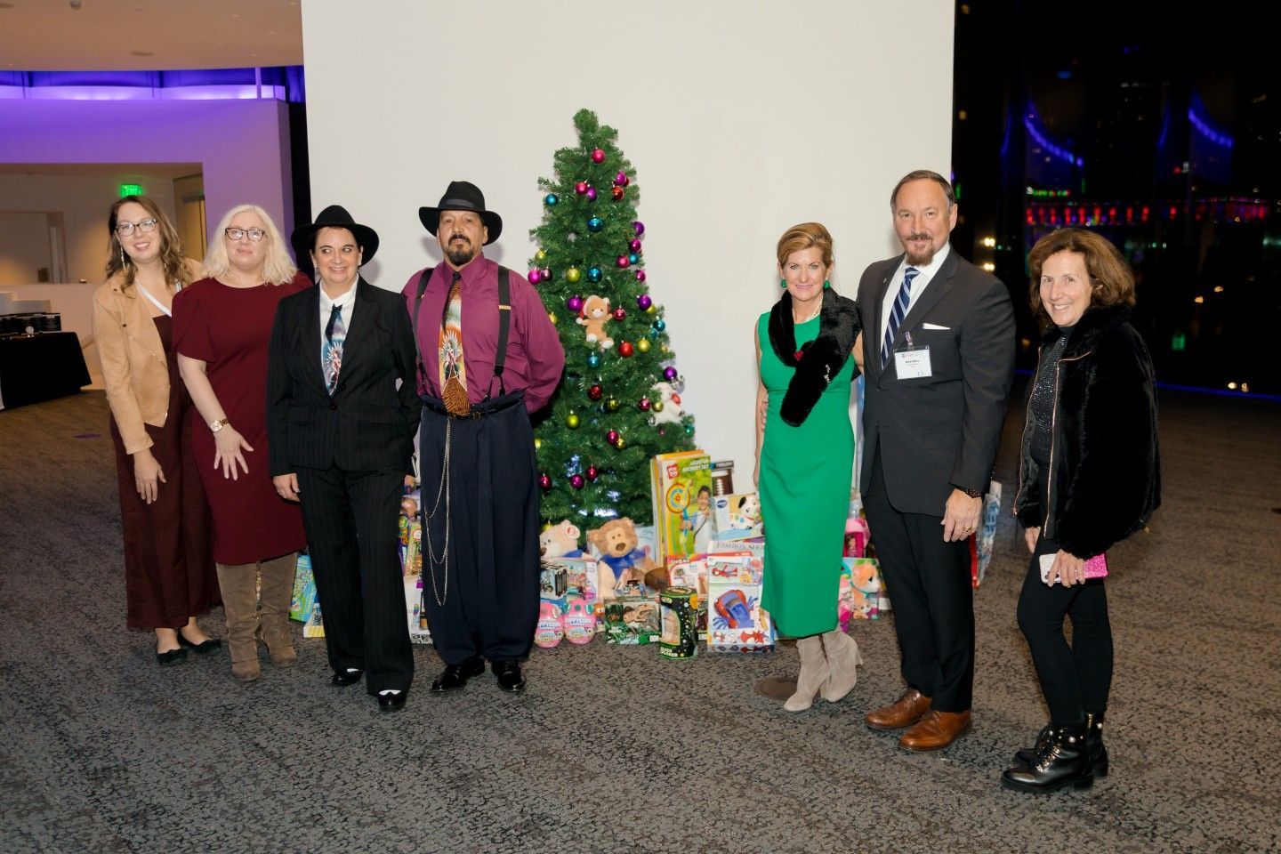 Group of people pose with Christmas tree and toys.