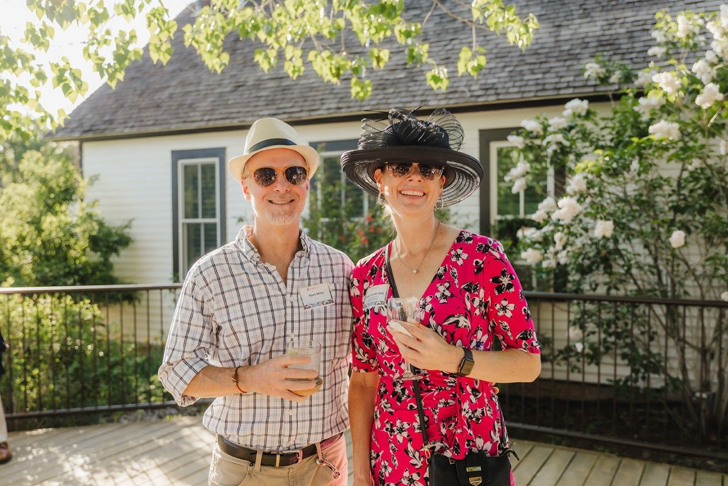 Couple in hats, sunglasses, and summer attire stand outdoors