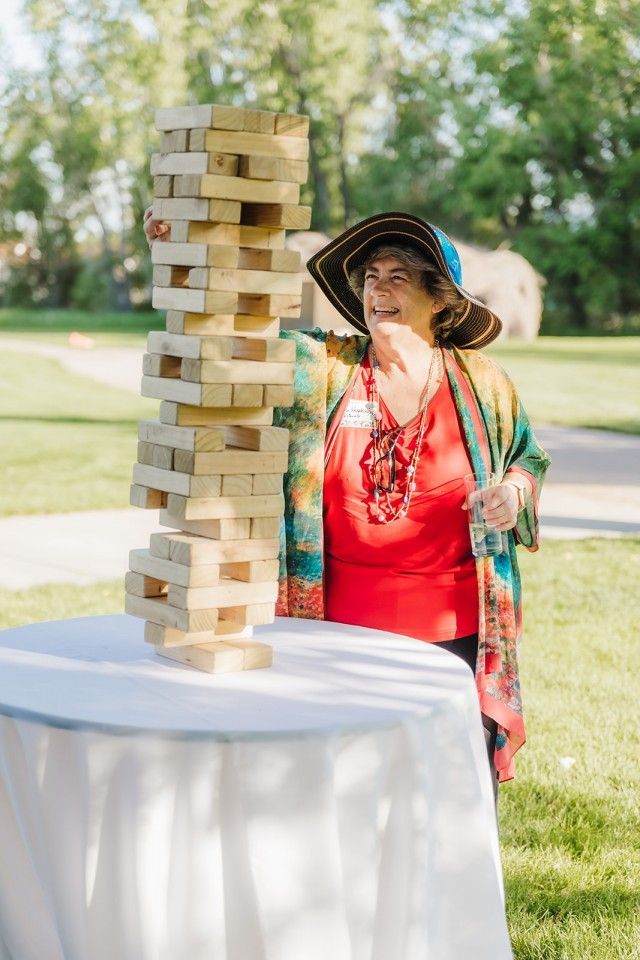 Woman playing giant Jenga game outdoors, smiling.