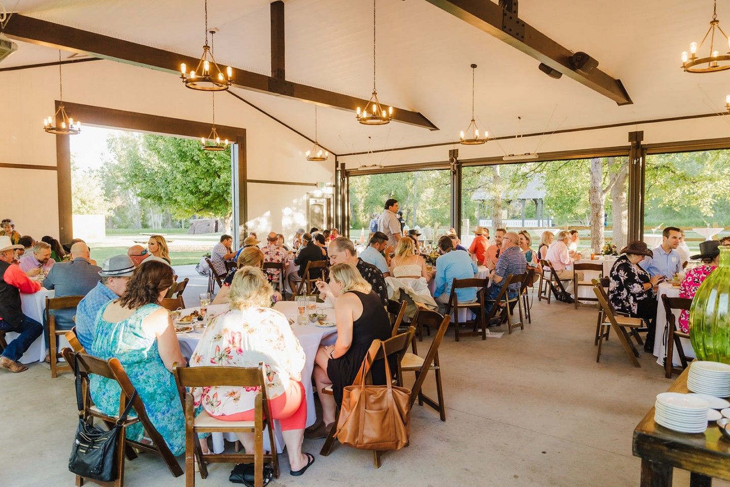 People seated at tables under a pavilion, enjoying a gathering outdoors.