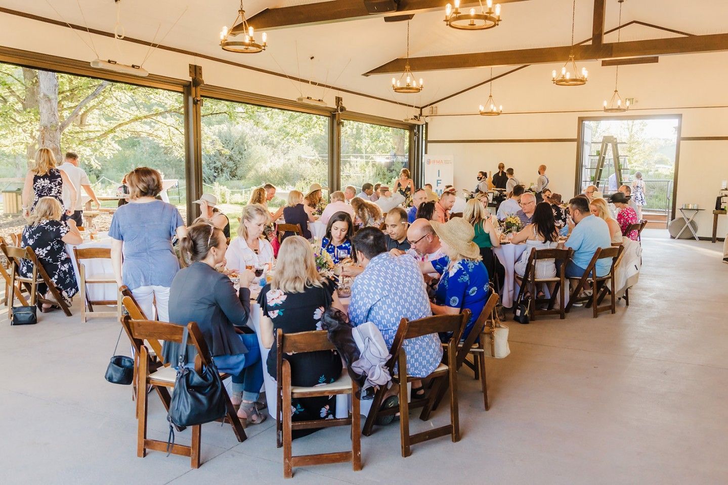 Guests seated at round tables in a pavilion, enjoying a gathering.