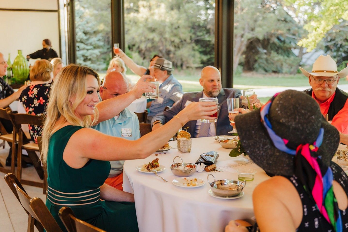 People toasting at a wedding reception; a woman in a green dress raises her glass.