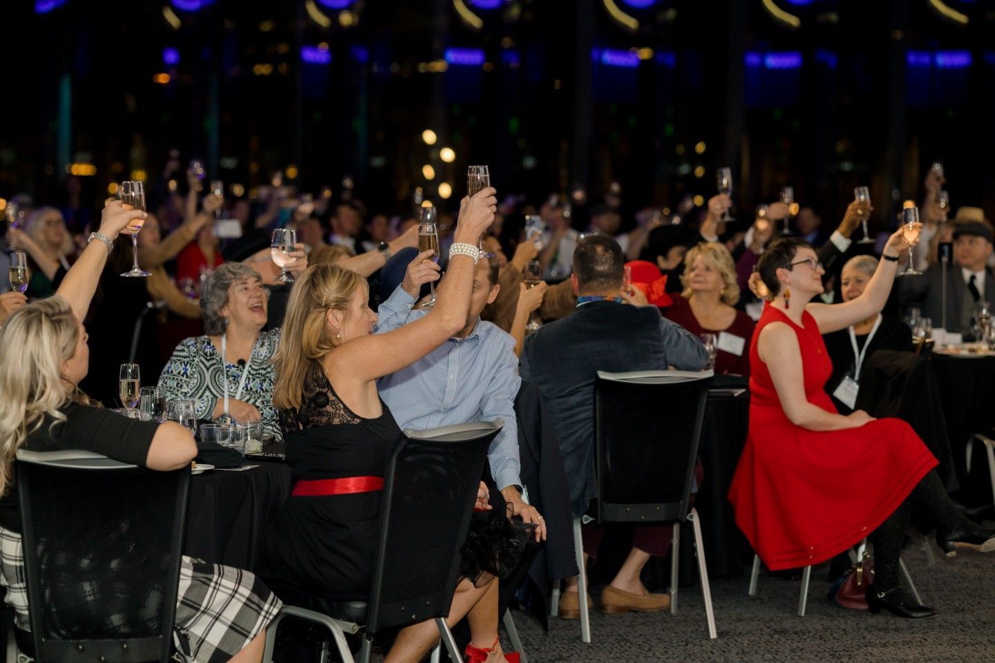 People at an event raising champagne glasses in a toast, festive atmosphere.