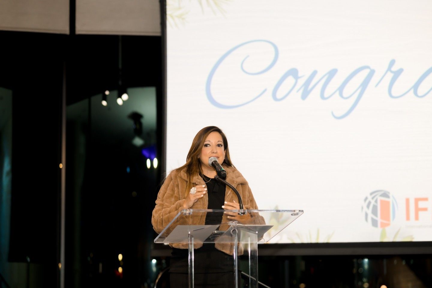 Woman speaking at a podium with a 