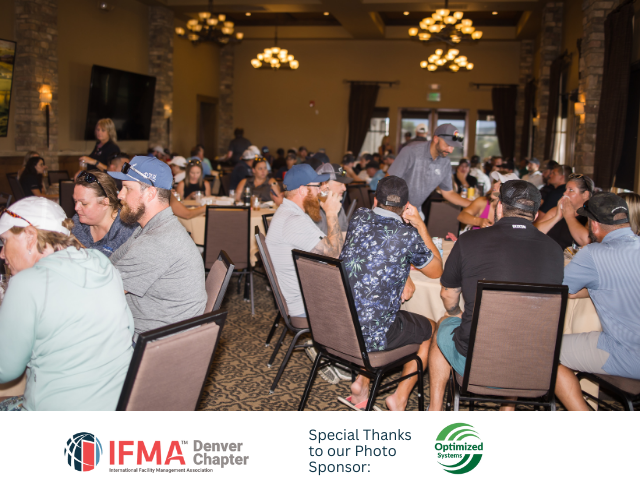 People seated at tables in a banquet hall. Some wear golf hats. Servers move among the diners.