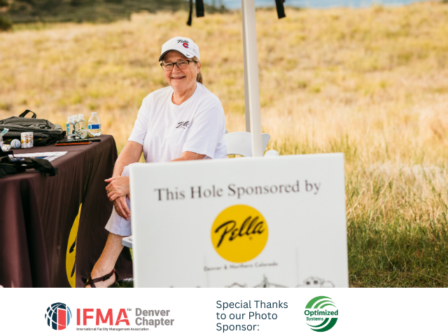 Woman at a golf event sponsored by Pella. She sits at a table near a sign on a sunny day.