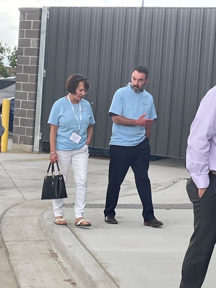 Woman in white pants and man in black pants walk and talk outside.