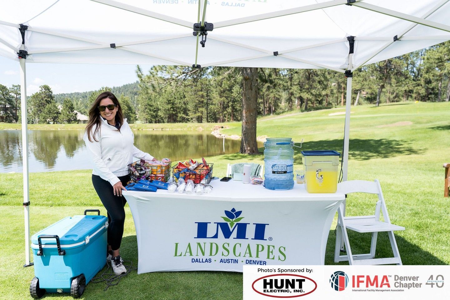 Woman stands behind a table at a golf event, branded 