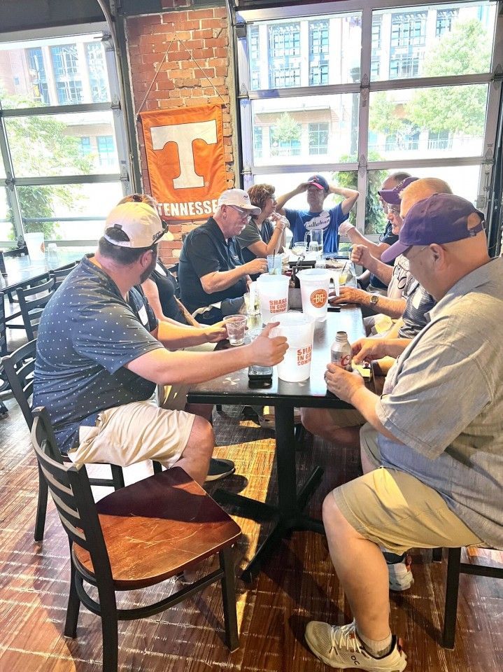People eating at a table in a restaurant; orange Tennessee Volunteers banner in the background.