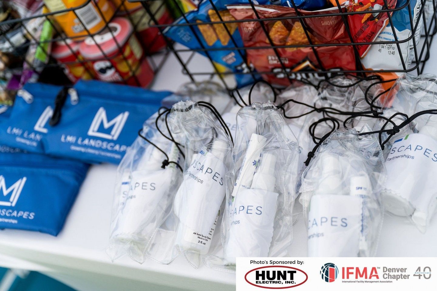 Snacks and bottled hand sanitizer in clear bags, branding for LMI Landscapes, and sponsors' logos.