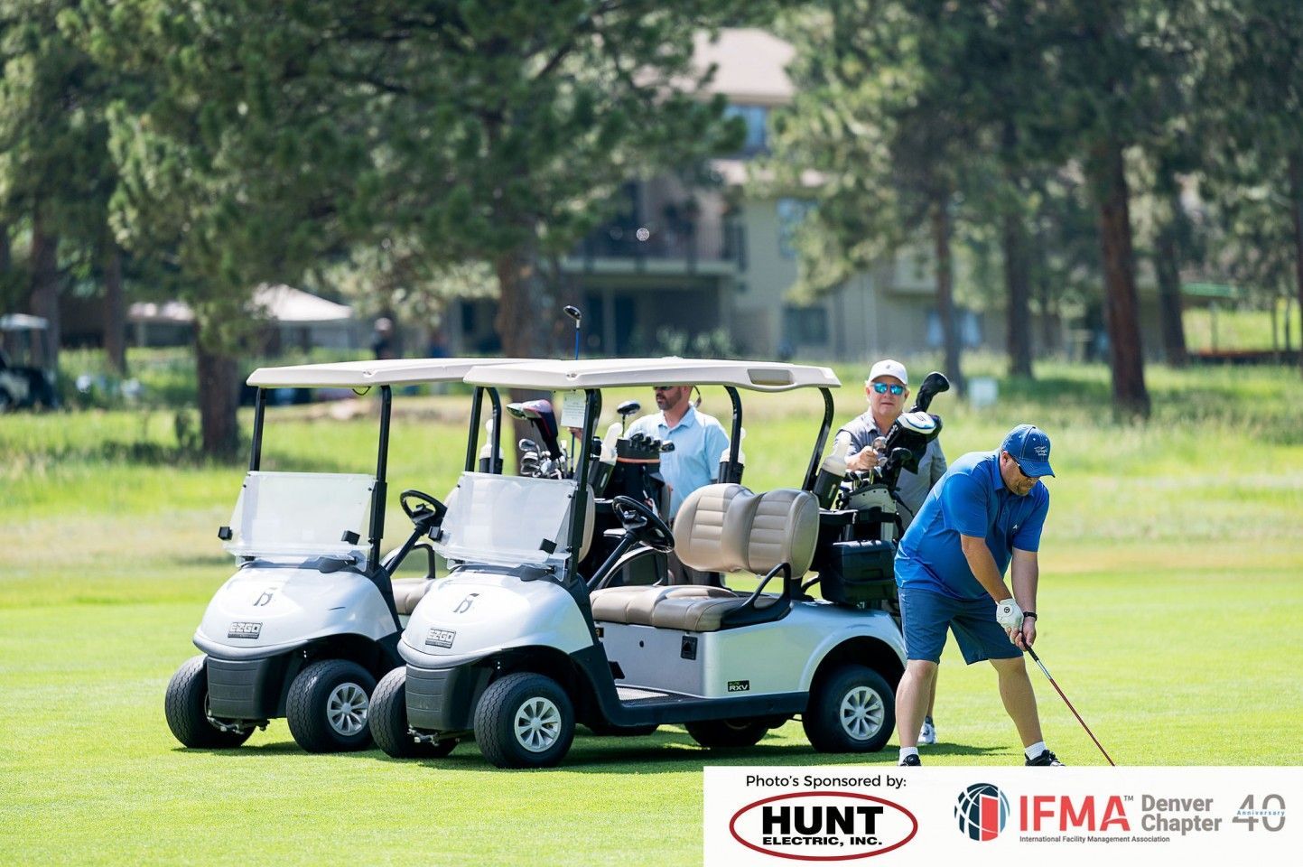Golfers playing golf with golf carts on a green golf course on a sunny day.
