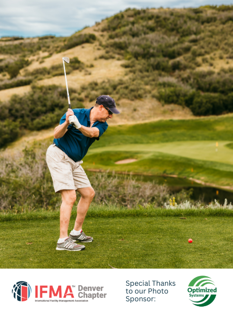 Man swings golf club on a green course, mountain in background.