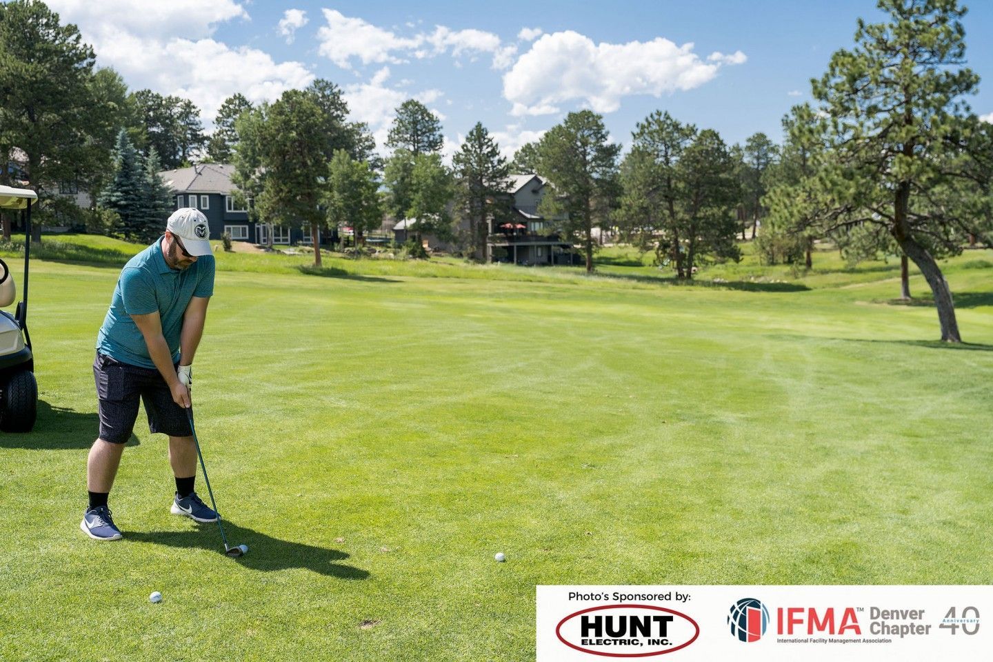 Man golfing, preparing to swing club on green. Golf cart nearby, sunny day.