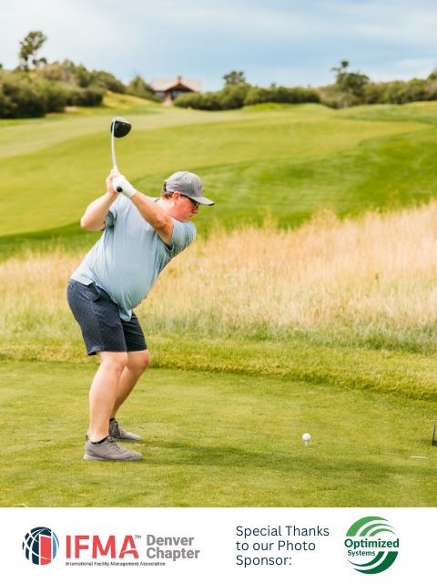 Man swings golf club on a green course, with a ball teed up and a blue sky overhead.