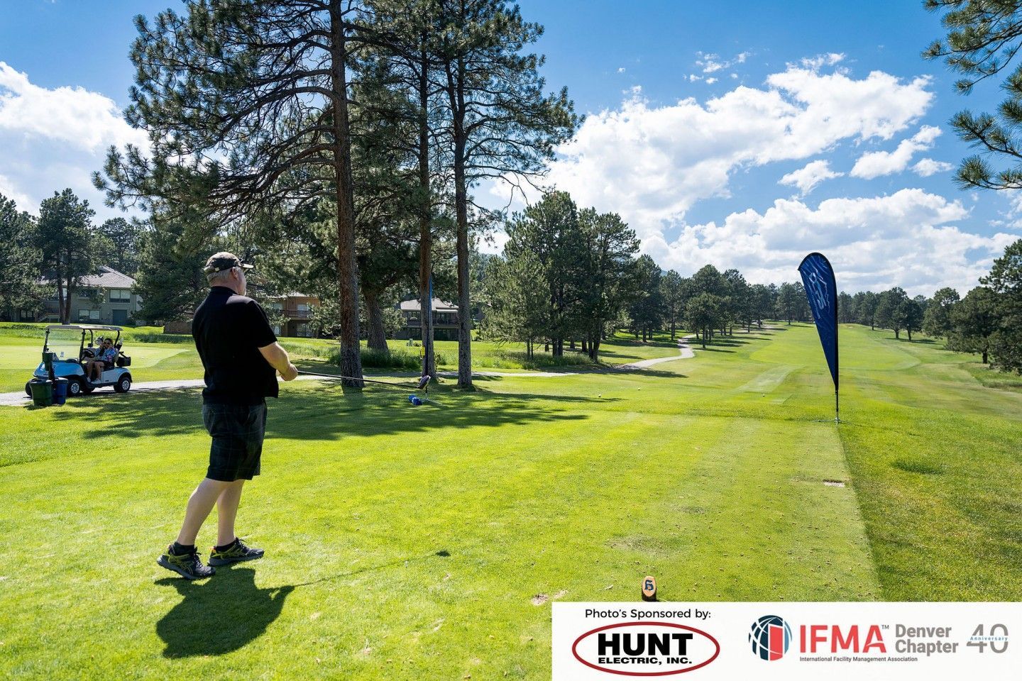 Man golfing on a green fairway, a golf cart nearby under a sunny sky.