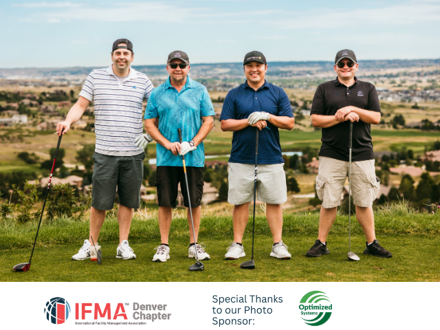Four men stand on a golf course, holding clubs. Mountain backdrop with blue sky and green grass.