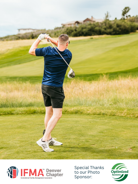 Man swings golf club on a green course, wearing blue shirt and black shorts.