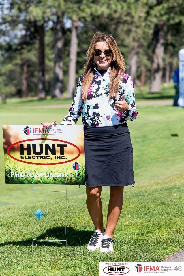 Woman in floral top and skirt stands by a 