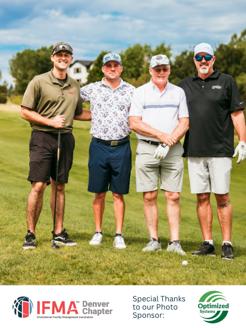 Four men on a golf course posing. Green field, sunny day. Two in caps, smiling.