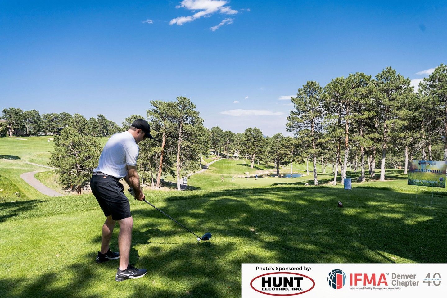 Golfer about to swing club on a green golf course, sunny day.