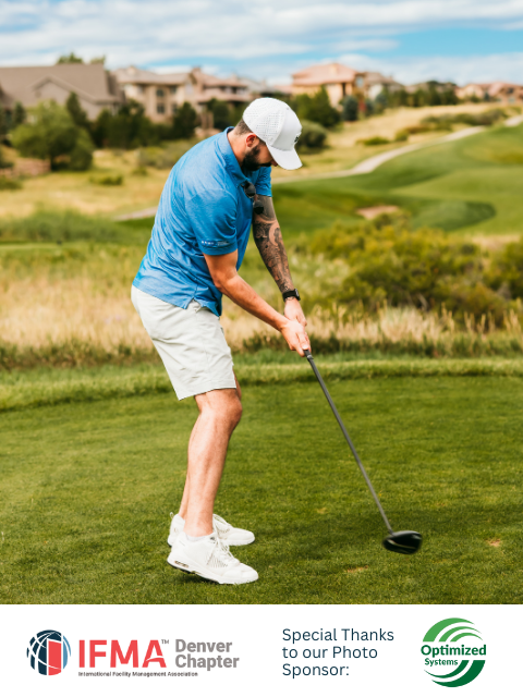 Man in blue shirt and white hat swings a golf club on a green course.