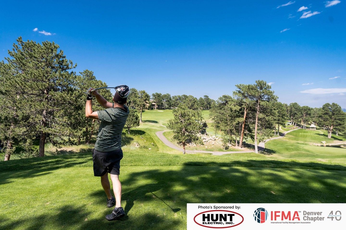 Golfer swinging a club on a sunny golf course.
