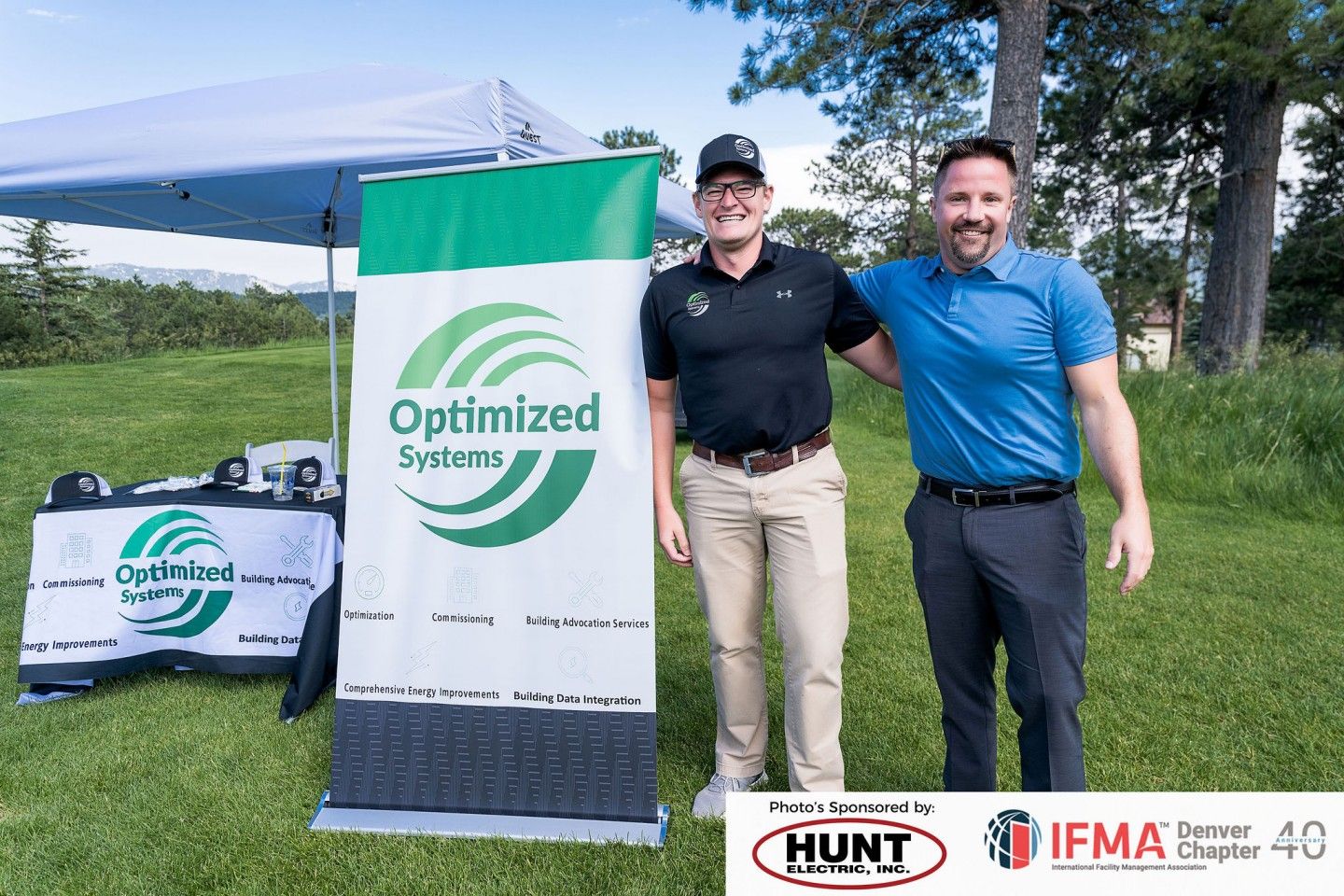Two men pose near a banner with the 