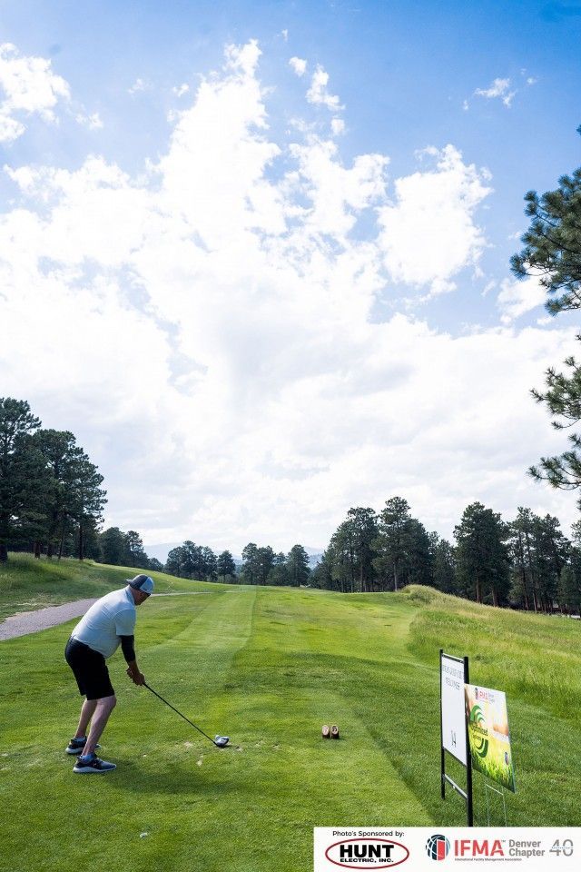 Golfer about to swing club on a green golf course, bright sunny sky.