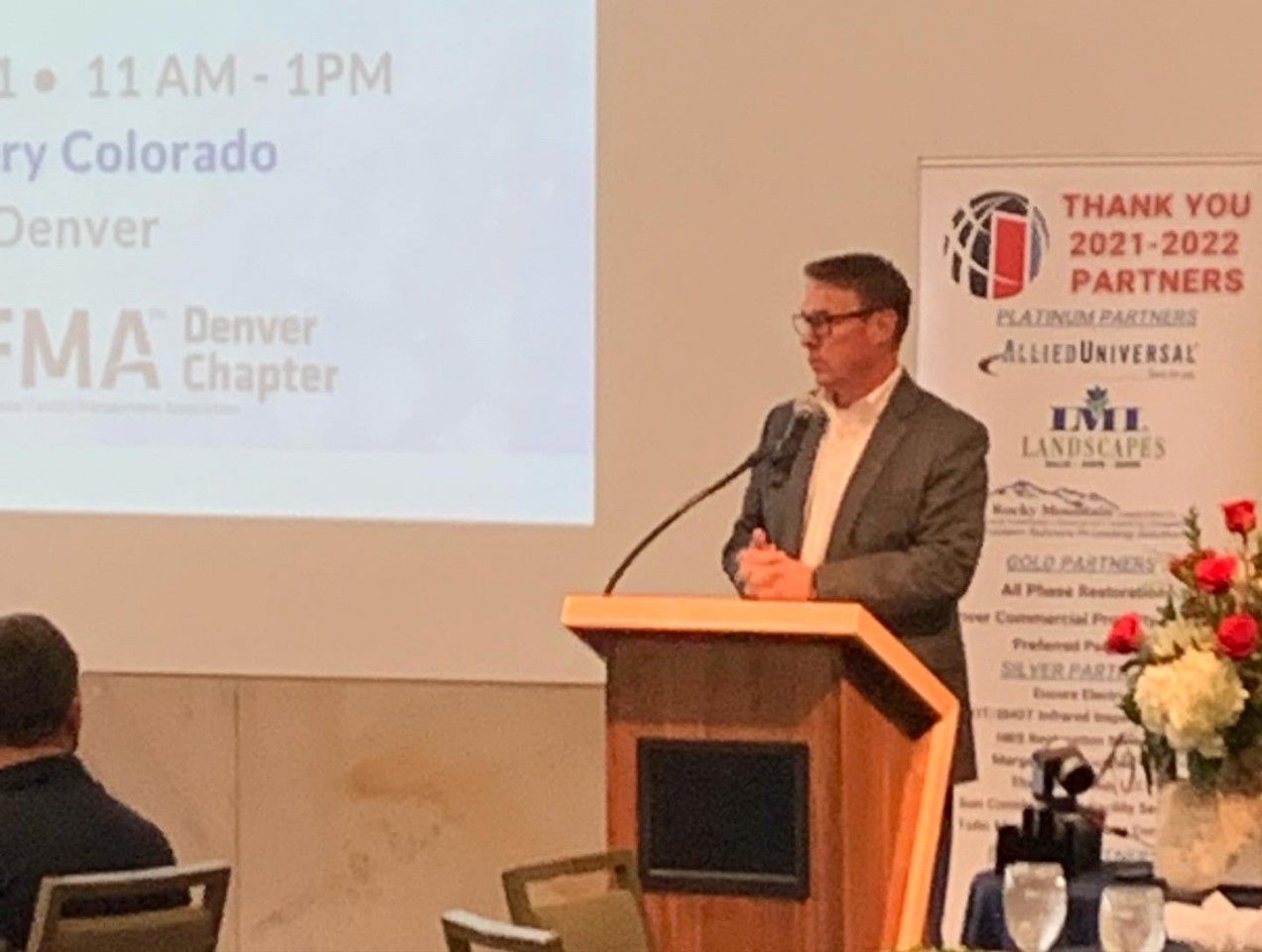 Man speaking at a podium in Denver, Colorado. Conference setting with 