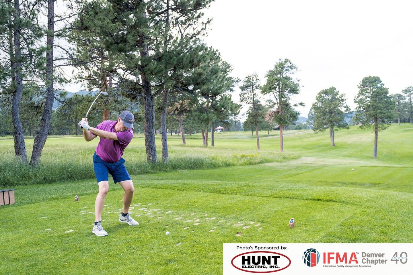 Man swinging a golf club on a green golf course.