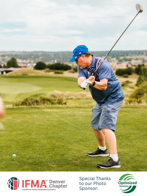 Man in blue shirt and hat swings golf club on a green course.